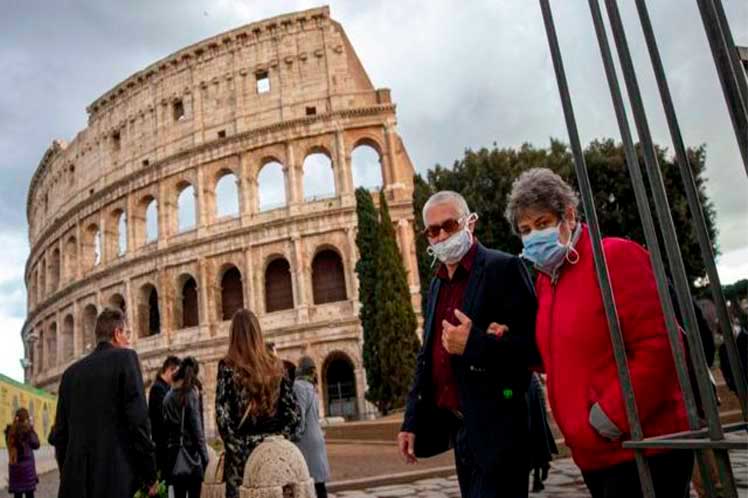 Italianos con tapabocas frente coliseo romano